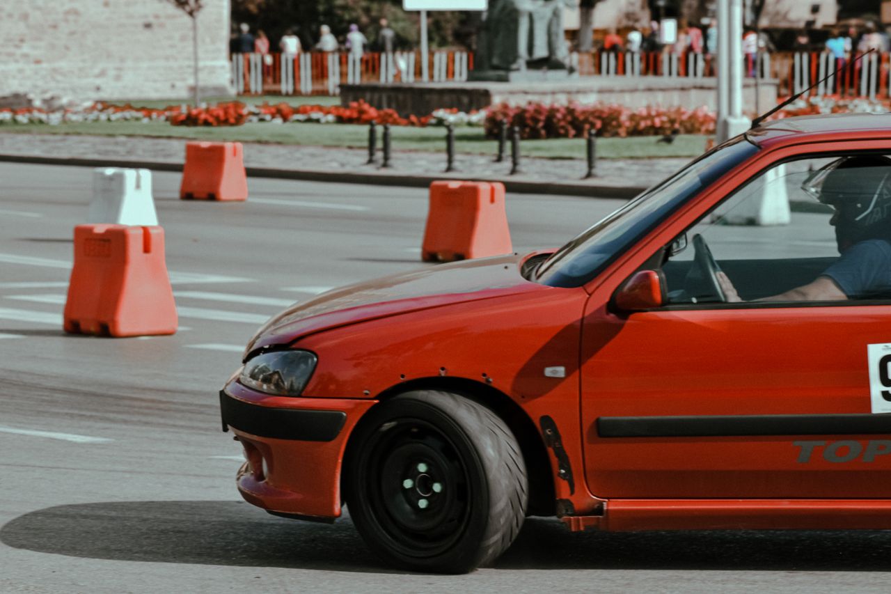 Red car driving and turning fast while racing on track of city street in sunny day