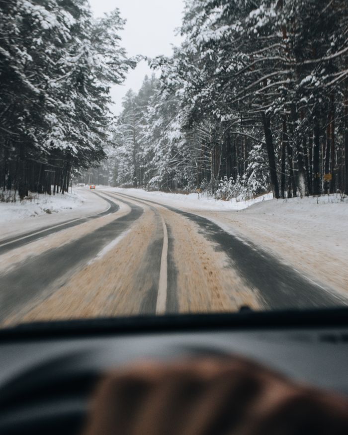 Capturing a serene winter drive through a snow-covered forest road.